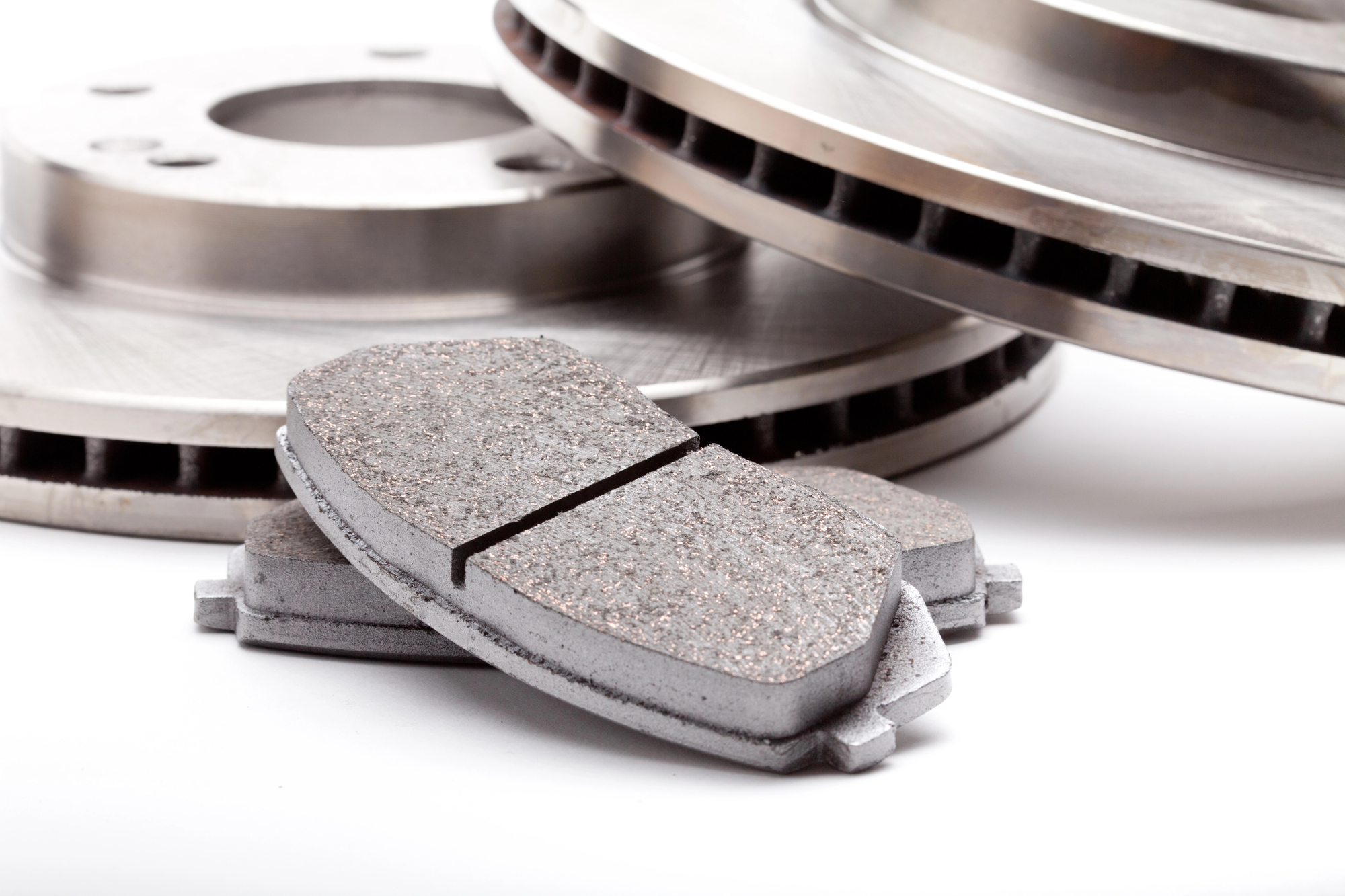 New brake pads in front of a pair of new brake rotors
