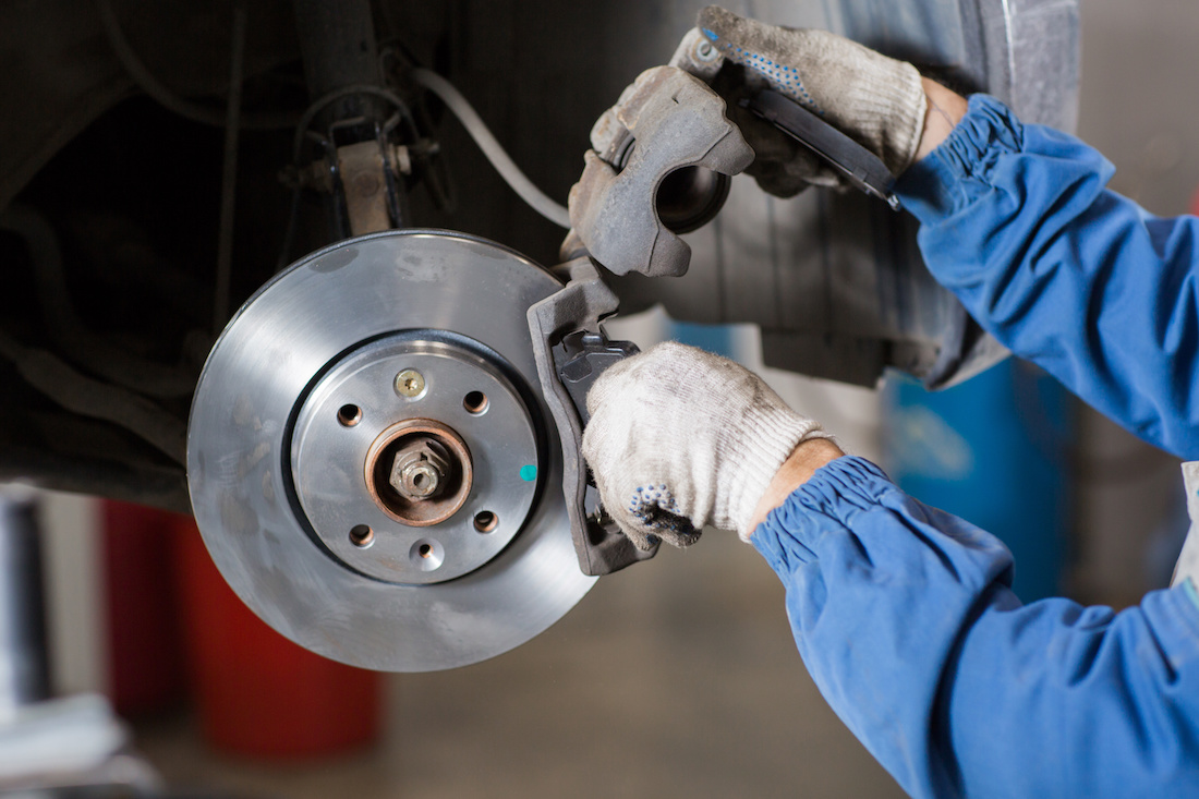 Technician fitting new brake pads onto a fresh rotor